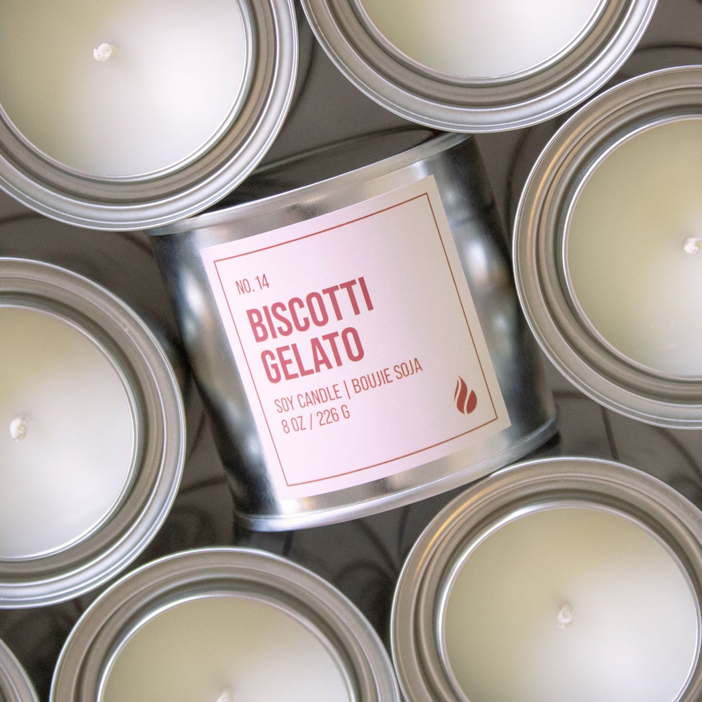 Photograph of Biscotti Gelato candle, label facing the screen, surrounded by candles facing up.