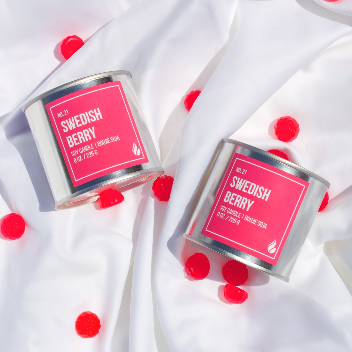 Picture of two Swedish Berry candles on top of a pure-white cloth sprinkled with Swedish Berry candies.