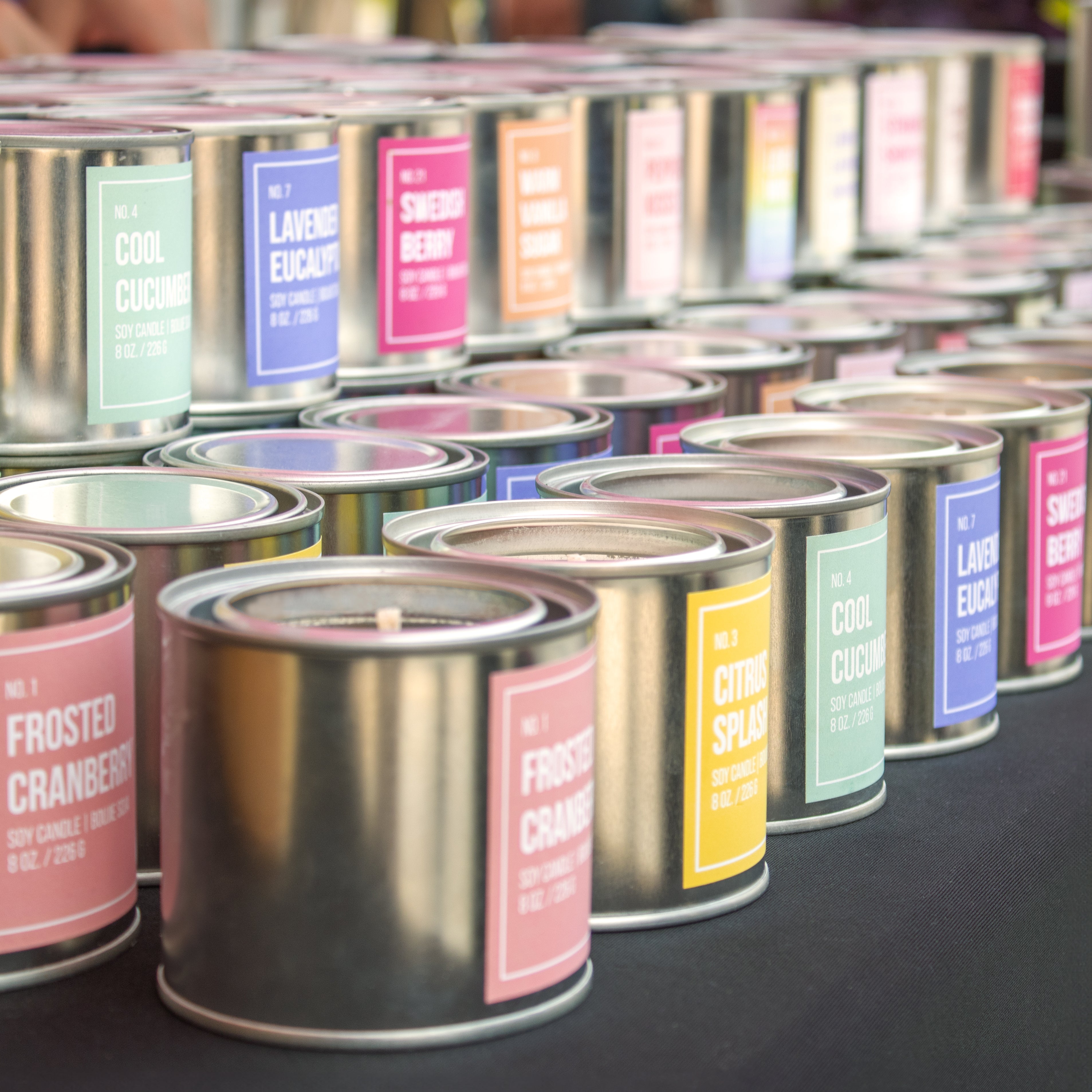 Picture of core line collection lined up next to each other place on a black cloth. Candles featured in order of left to right are:  Frosted Cranberry, Citrus Splash, Cool cucumber, Lavender Eucalyptus, Swedish Berry, Warm Vanilla Sugar, Peppermint Kisses, Love Always Wins, Lemon Lavender Shortbread, Strawberry Shortcake, Biscotti Gelato, and Maraschino Cherry.
