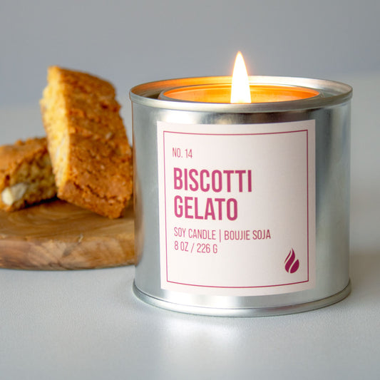 Photo of Biscotti Gelato candle lit up next to a plate of biscotti.