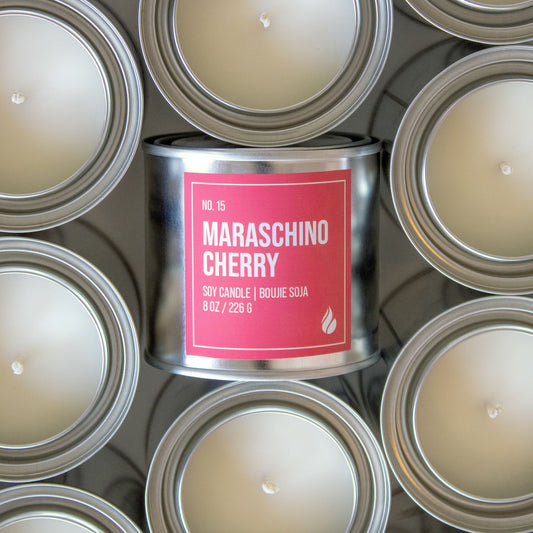 Photograph of Maraschino Cherry candle, label facing the screen, surrounded by candles facing up.